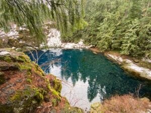 Blue Pool lagoon with a dusting of snow and evergreen trees all around the lagoon